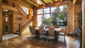 Un interior de madera con comedor, escalera y ventanas amplias.