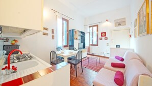 A compact living space with a kitchenette, dining area, and a sofa with cushions. - DolceVita Apartments N. 408 (Venice)