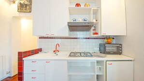 A compact kitchen with white cabinets, a gas stove, a microwave, and a tiled backsplash. - DolceVita Apartments N. 408 (Venice)