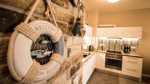 A kitchen with white cabinets, a stove, and a coffee maker. - Baltic Apartments - Apartament Aurora (Swinoujscie)