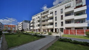 A modern apartment building with multiple balconies, a well-maintained lawn, and a clear sky. - Baltic Apartments - Apartament Aurora (Swinoujscie)