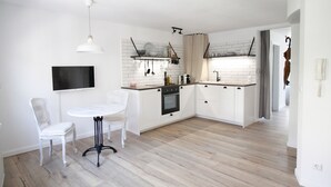A modern kitchen with white cabinetry, a marble countertop, and a dining area with two white chairs. - Boutique Charme Apartments 10 (Baden-Baden)