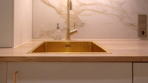 A kitchen with a gold sink, marble backsplash, and a modern faucet. - Boutique Charme Apartments 10 (Baden-Baden)