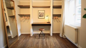 A room with a wooden floor, a desk with a chair, a framed picture on the wall, and a radiator. - Boutique Charme Apartments 10 (Baden-Baden)
