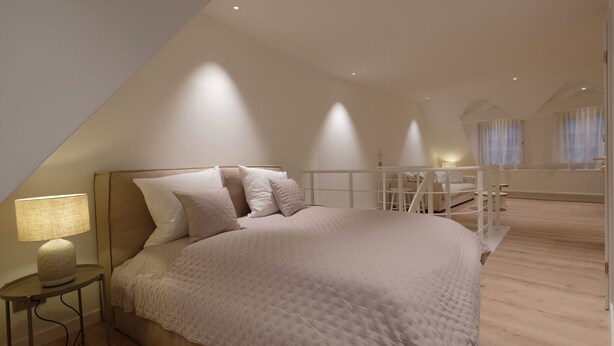 A bedroom with a large bed, a nightstand, and a desk. - Boutique Charme Apartments 10 (Baden-Baden)