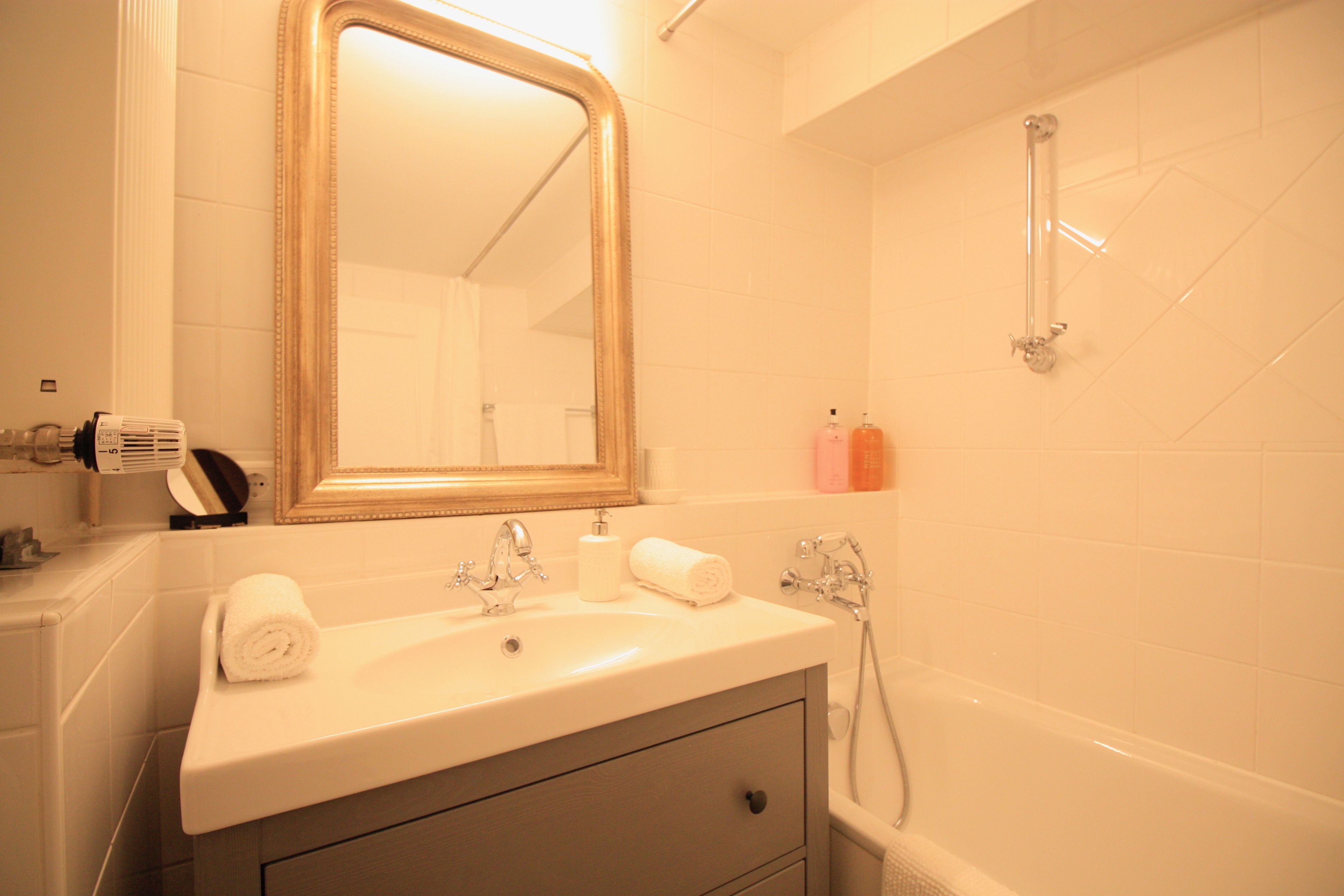 A bathroom with a sink, mirror, and shower.