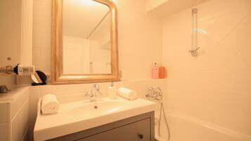 A bathroom with a sink, mirror, and shower.