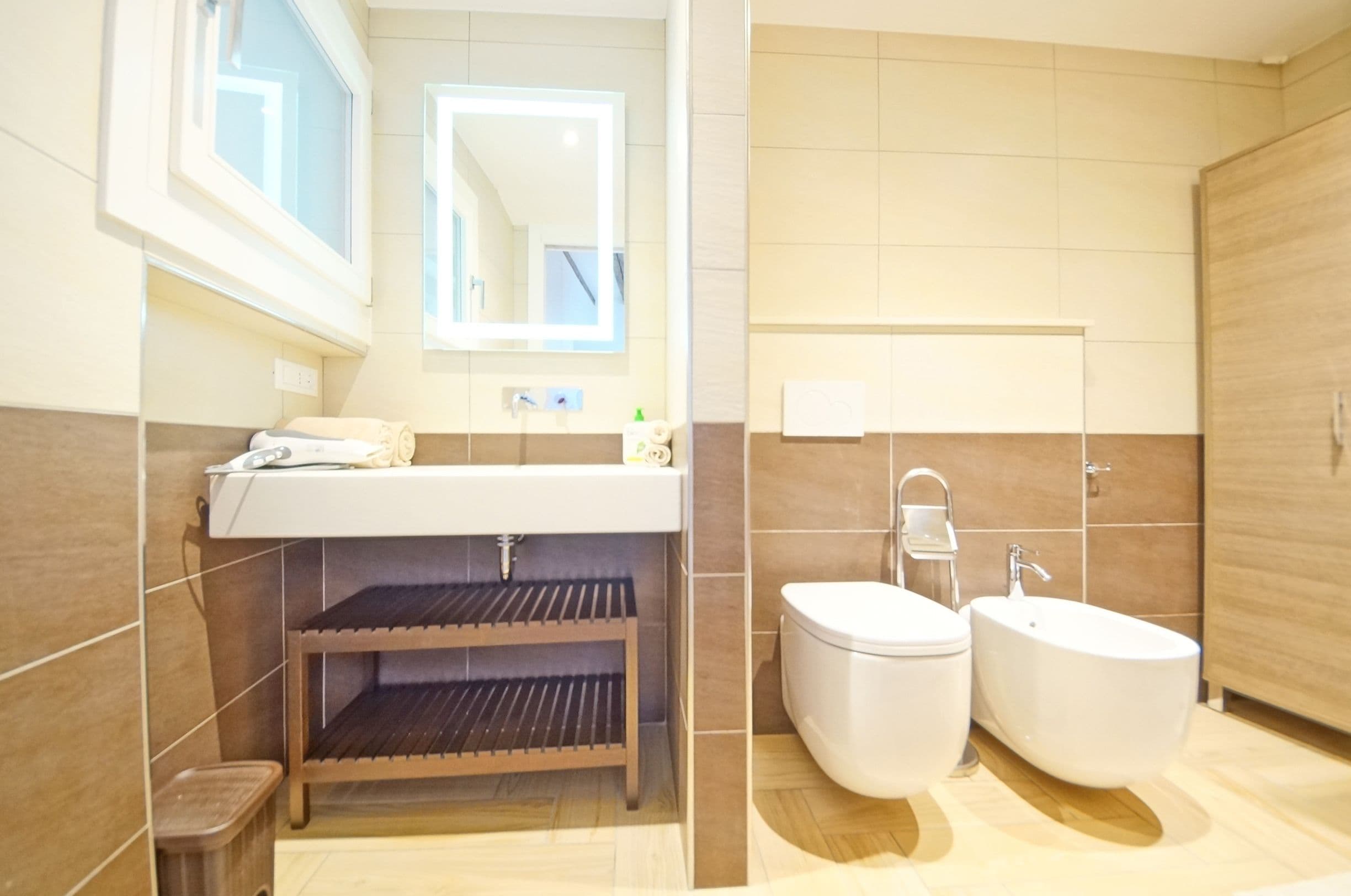 A modern bathroom with a sink, mirror, toilet, and bidet.