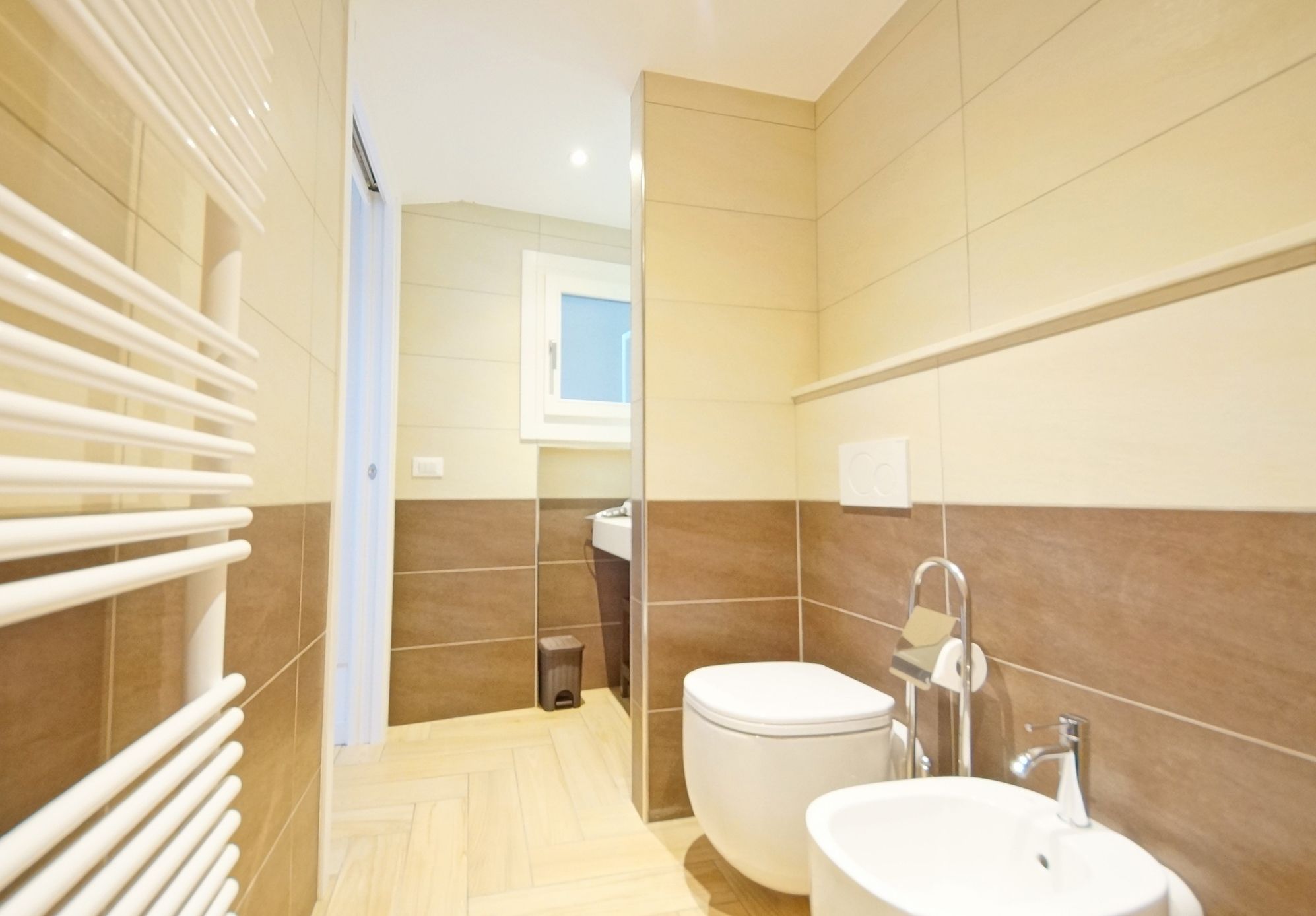 A modern bathroom with a toilet, sink, and a towel rack.