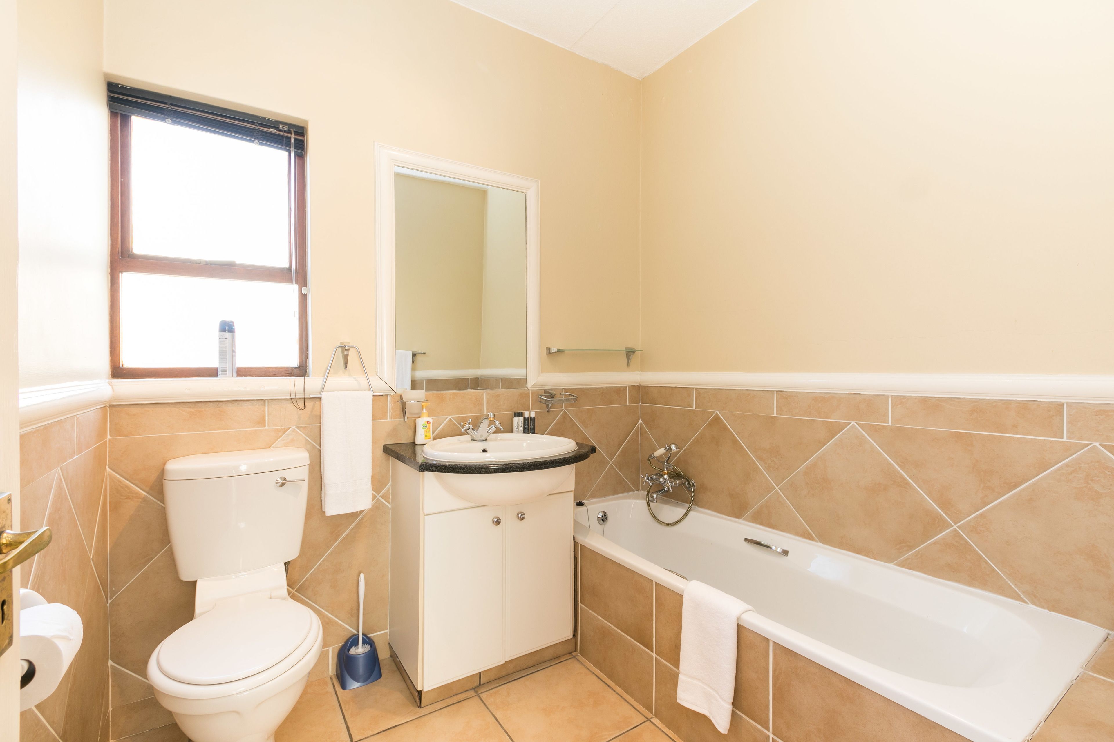 A bathroom with a toilet, sink, mirror, and bathtub.