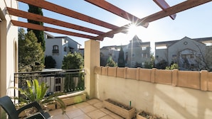 Ein Balkon mit Holzbalken, Blumentöpfen und Blick auf benachbarte Gebäude.