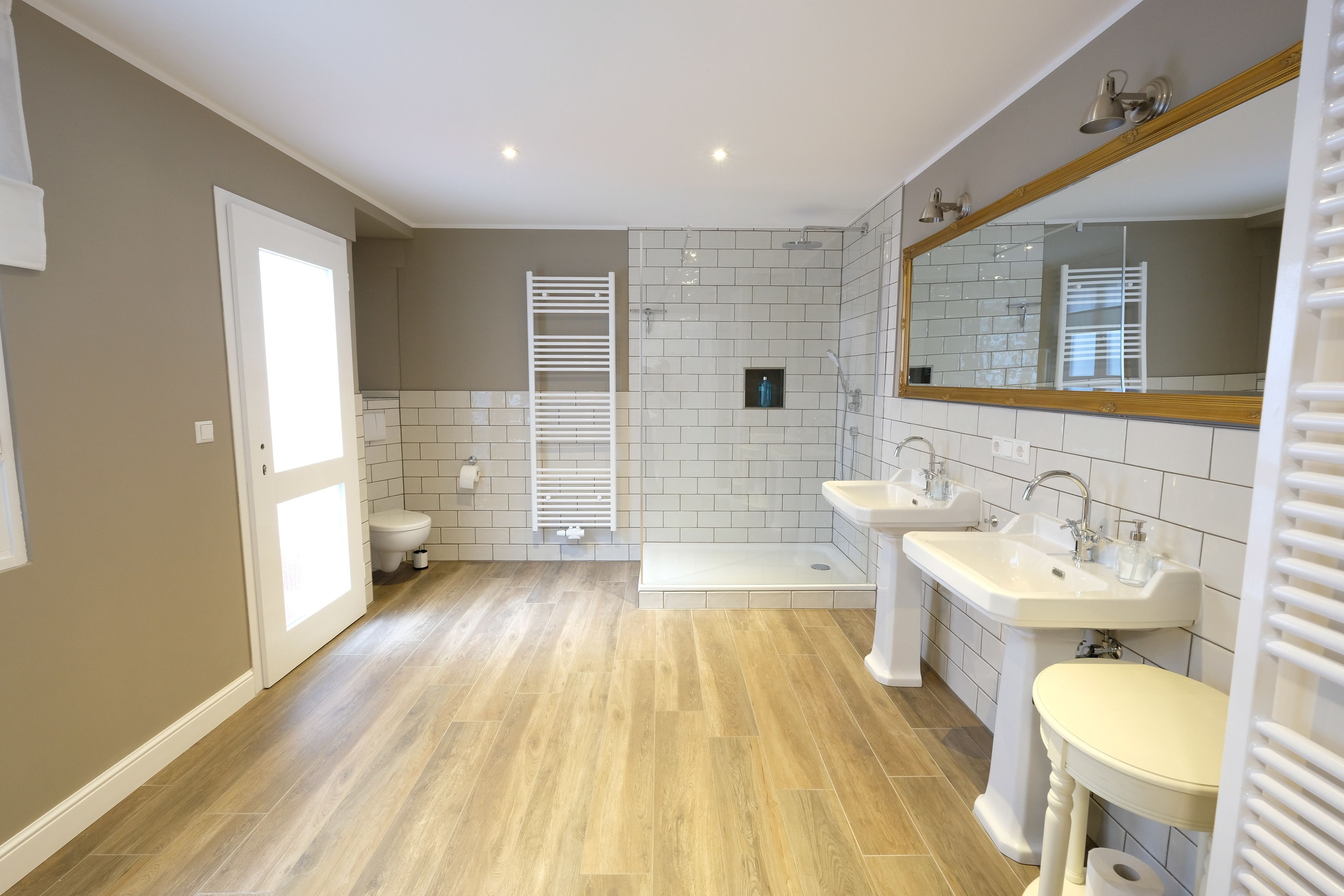 A modern bathroom with a shower, two sinks, and a toilet.