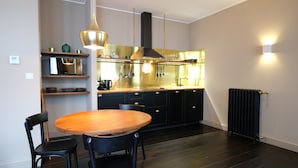 A modern kitchen with dark wood flooring, a round wooden table, and black chairs. - Boutique Charme Apartments 5 (Baden-Baden)
