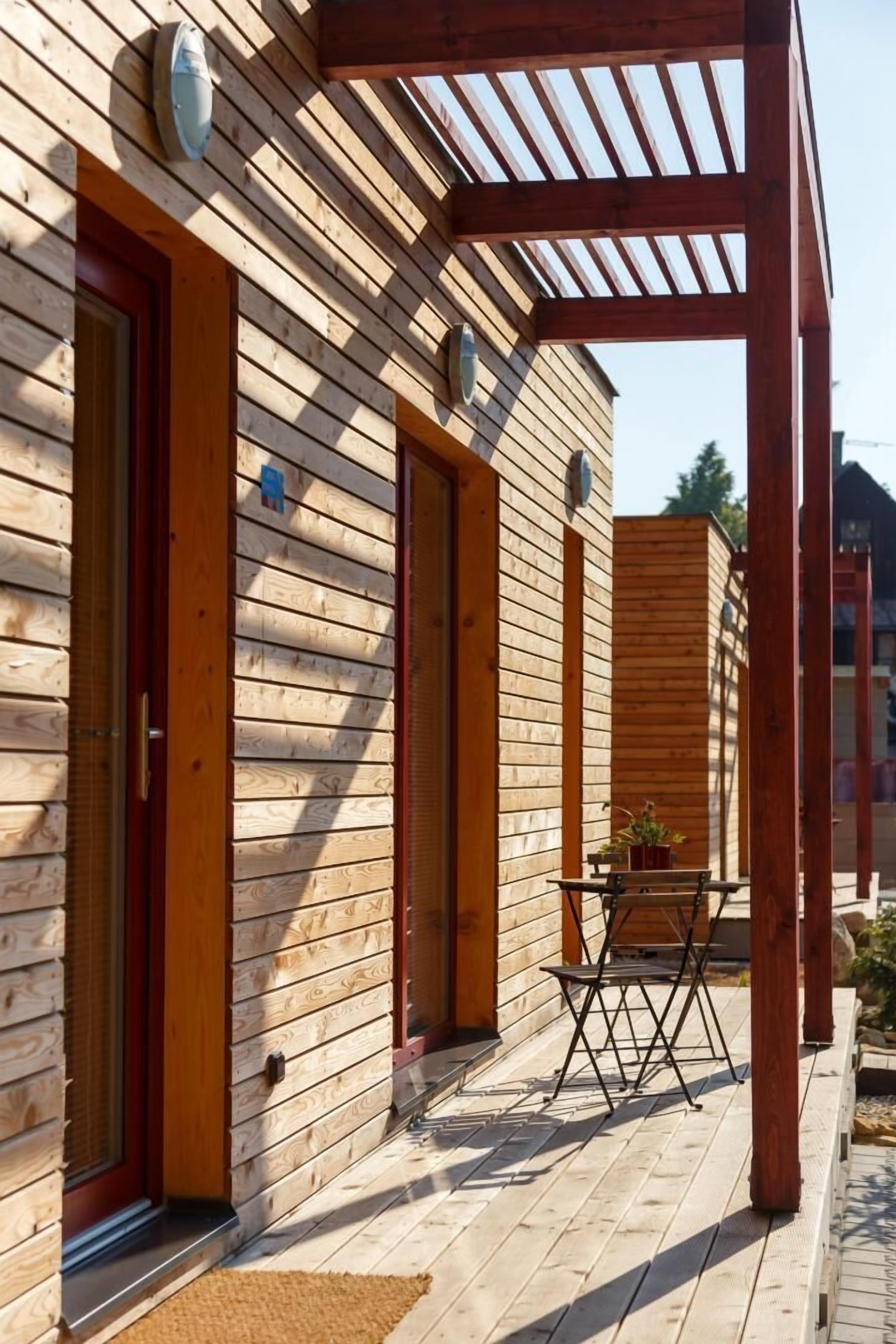 Una cabaña de madera con un porche cubierto, una puerta y una ventana.
