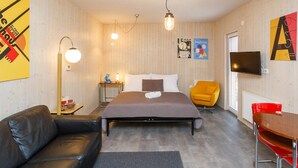 Una habitación de hotel moderna con cama, sofá, escritorio y televisor.