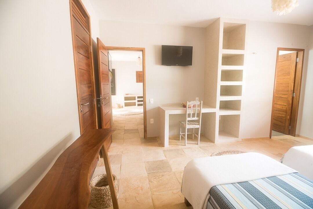 A bedroom with a bed, a desk, and a TV.