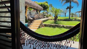 Una hamaca en una habitación con vista a un jardín y una construcción de techo de paja.