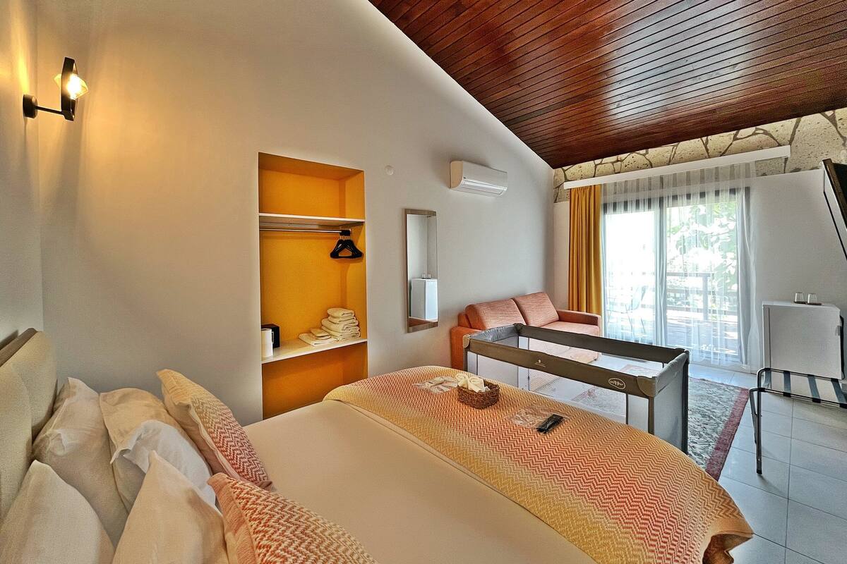 A hotel room with a bed, a seating area, a wardrobe, and a window with curtains.