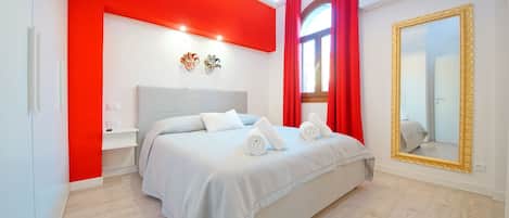 Un dormitorio moderno con una cama grande, una mesita de noche, un espejo y cortinas rojas.