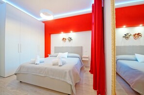 Ein modernes Hotelzimmer mit einem großen Bett, einem Kleiderschrank und einer auffälligen roten Akzentwand.