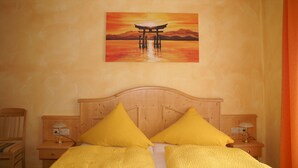 A hotel room with a wooden bed, two nightstands, and a painting of a traditional structure on the wall.