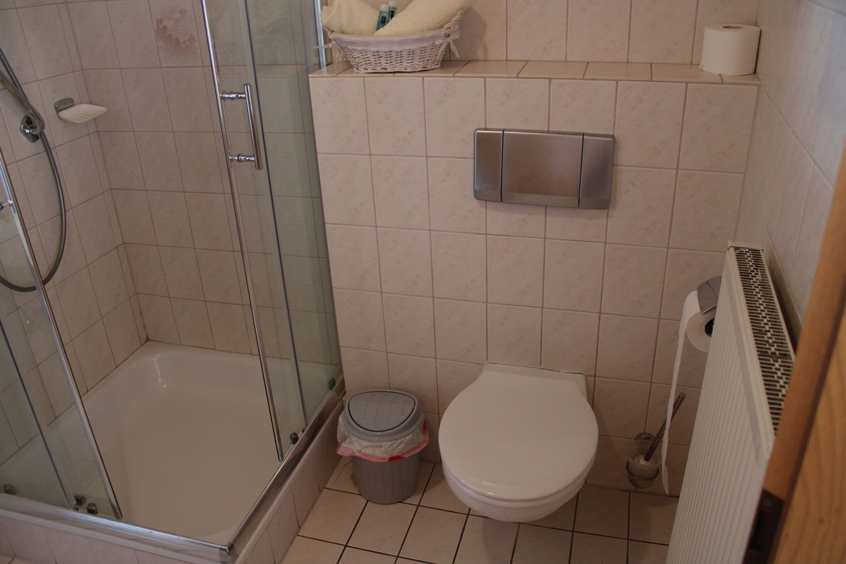 Ein Badezimmer mit einer Duschkabine, einer Toilette und einem Mülleimer.
