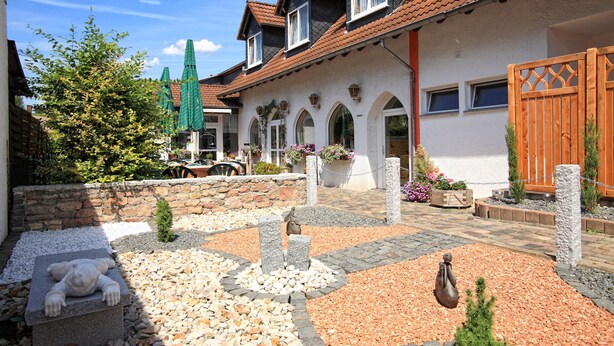 A courtyard with a stone bear sculpture, a stone fountain, and a wooden fence.