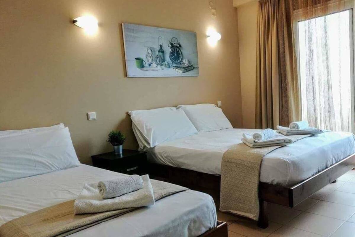 A hotel room with two beds, a painting on the wall, and a window with curtains.