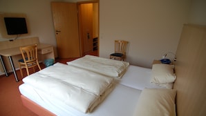 A hotel room with a bed, a desk, a chair, a TV, and a wardrobe. - Catharinenberg (Molfsee)