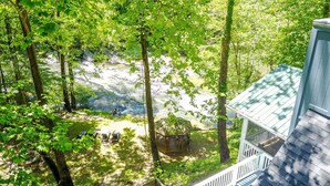 A view from a balcony overlooking a river, surrounded by trees, with a gazebo and lounge chairs visible. - Stunning Rushing River Views  ~ North Georgia Mountains ~ Short Hop to Town! (Dahlonega)
