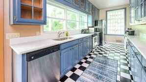 A kitchen with blue cabinets, a black and white checkered floor, and a dishwasher. - Stunning Rushing River Views  ~ North Georgia Mountains ~ Short Hop to Town! (Dahlonega)