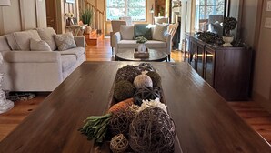 A spacious living room with a wooden coffee table, a chandelier, and a large window. - Stunning Rushing River Views  ~ North Georgia Mountains ~ Short Hop to Town! (Dahlonega)