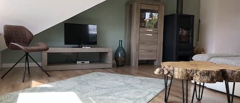 A modern living room with a TV, wooden entertainment unit, and a rustic dining table.