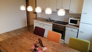Eine moderne Küche mit weißen Schränken, einem schwarzen Herd, einer Mikrowelle und Pendelleuchten.