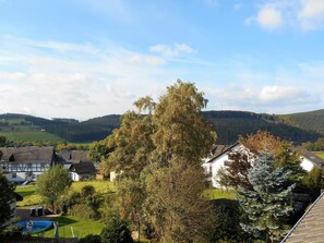 A residential area with houses, a swimming pool, and a large tree in the foreground. - Apartment Katya (Winterberg)