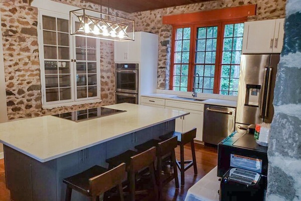Brand new kitchen featuring quartz countertops, cooktop, oven and refrigerator.