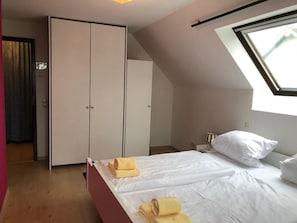 A bedroom with a bed, a wardrobe, a skylight, and a window. - Apartment Azalea (Winterberg)