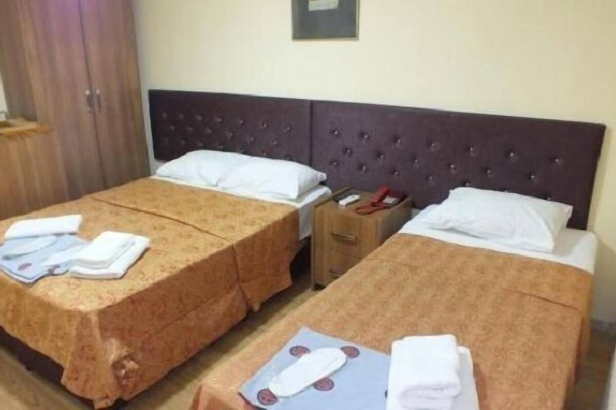 A hotel room with two beds, each with a headboard, a wooden nightstand, and a small table.