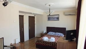 A hotel room with a bed, a TV, a desk, and a ceiling fan. - Naz Hotel (Istanbul)