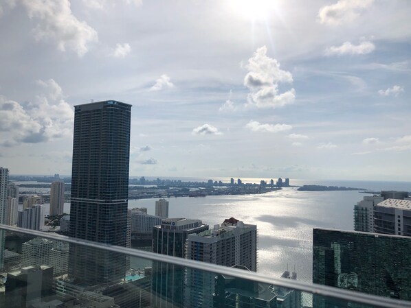 A high-rise building with a view of a body of water and a distant city skyline.