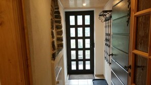 A narrow hallway with a tiled floor, a black door with glass panels, and a wooden door on the right. - Apartment Mühlenberg (Winterberg)