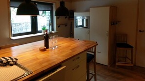 A kitchen with wooden countertops, a built-in oven, and a refrigerator. There is a window with a view of greenery outside. - Apartment Mühlenberg (Winterberg)