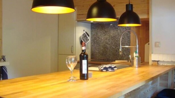 A kitchen with wooden countertops, a wine bottle, and two pendant lights. - Apartment Mühlenberg (Winterberg)