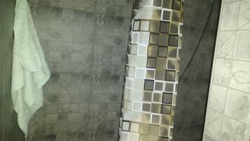 A bathroom with a shower curtain featuring a geometric pattern, tiled walls, and a hanging towel.