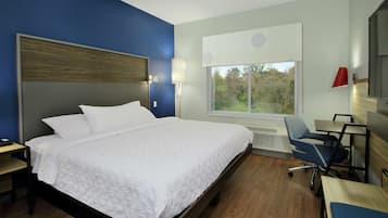 A modern hotel room with a large bed, a desk, and a chair.