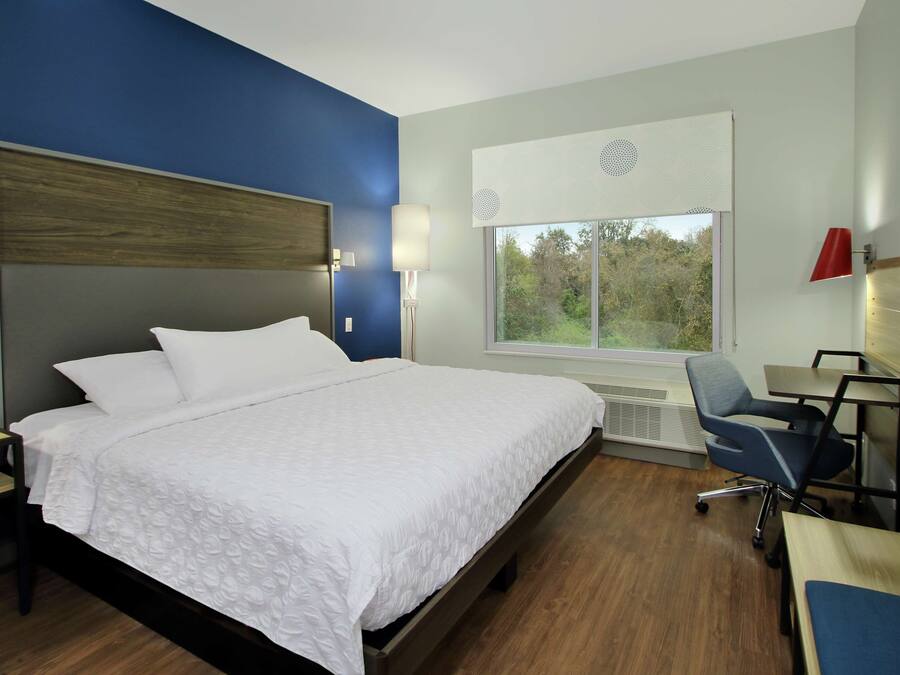 Una habitación de hotel moderna con una cama grande, un escritorio y una silla.