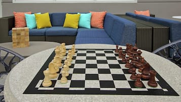 Un tablero de ajedrez con piezas, una pila de bloques de madera y un sofá azul con cojines coloridos.