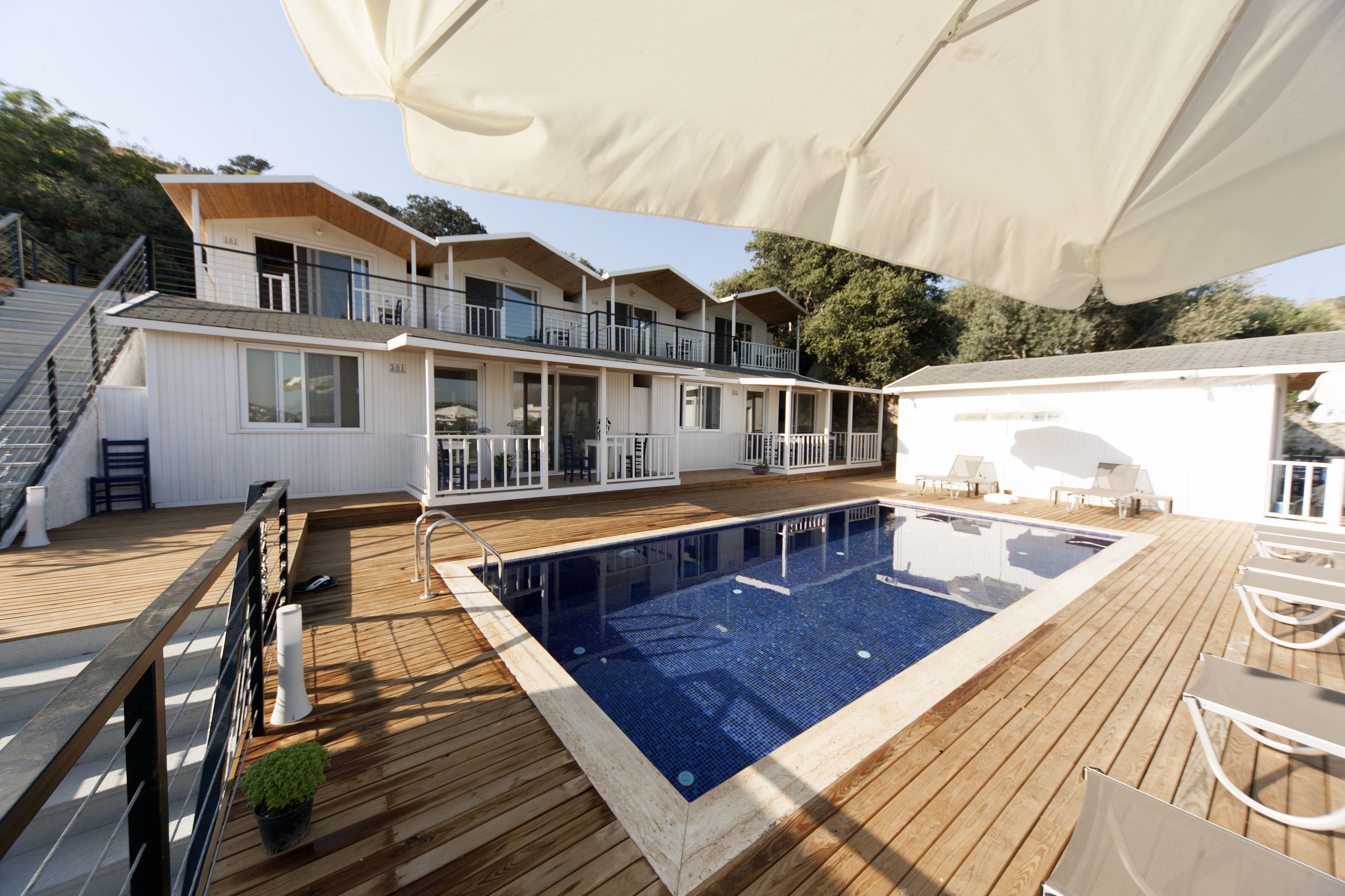 Un espace piscine doté d’une terrasse en bois, d’une piscine et d’un bâtiment comportant plusieurs balcons.