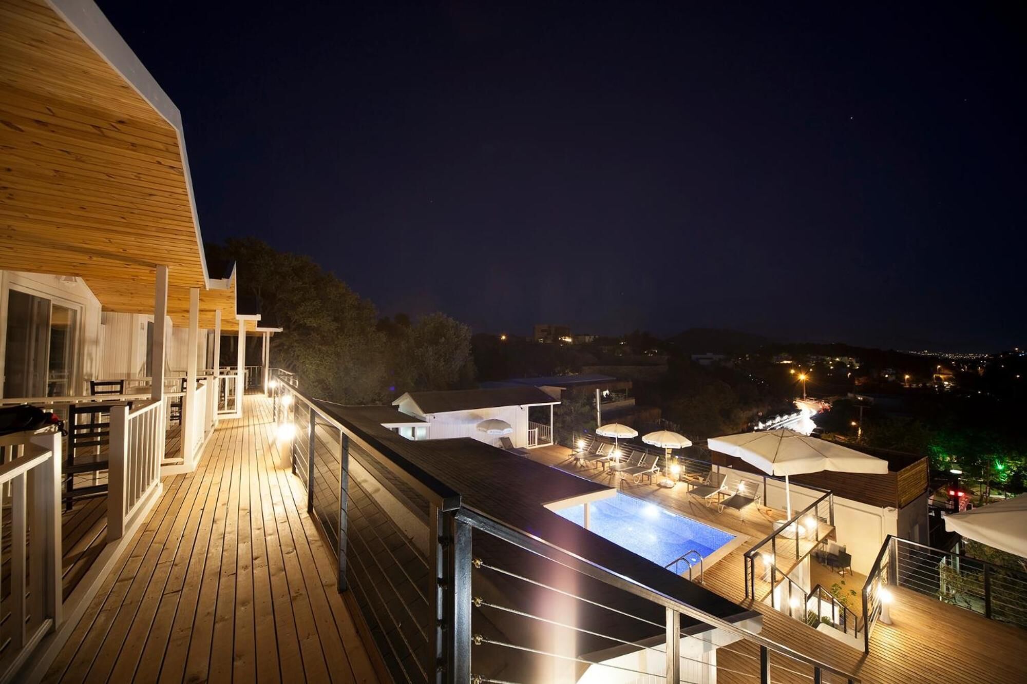 Una terrassa amb piscina, mobiliari exterior i vistes nocturnes de la ciutat.