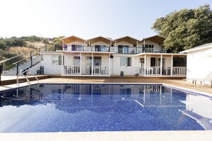 Un hotel moderno con piscina, varios balcones y una terraza de madera.